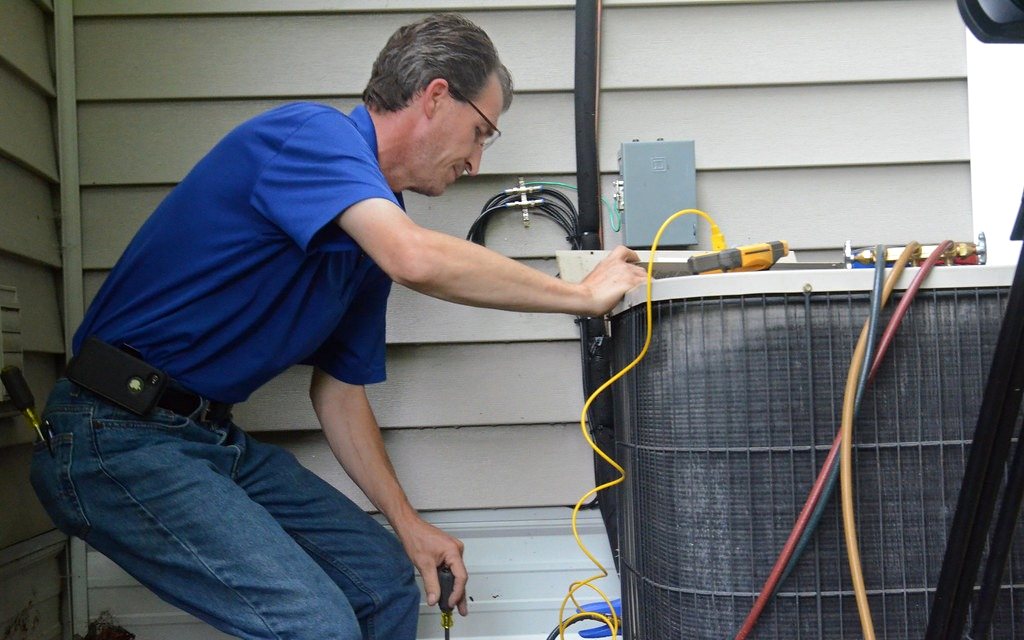 Technician servicing an air conditioner outdoor unit