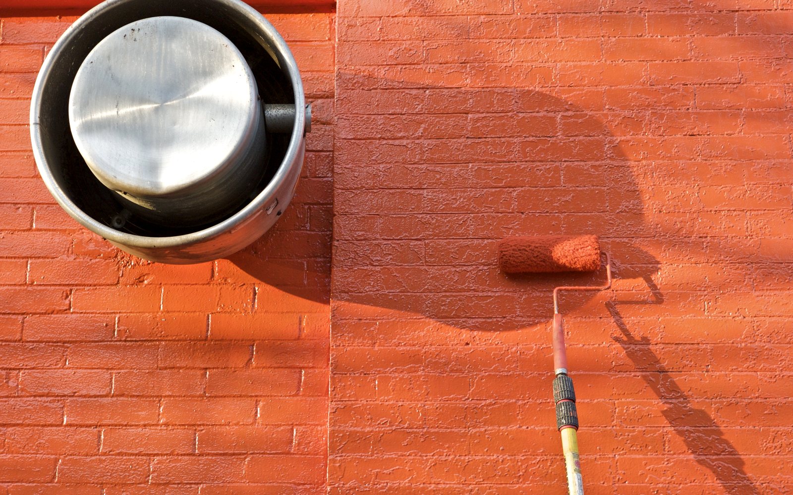 Paint roller painting a brick wall