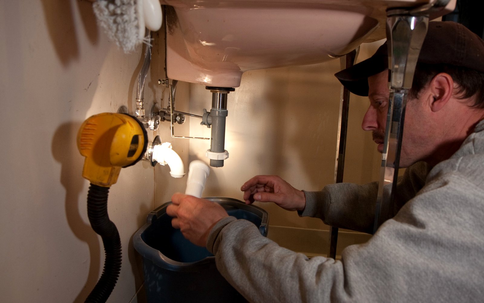 Plumber repairing the drain pipe under a sink